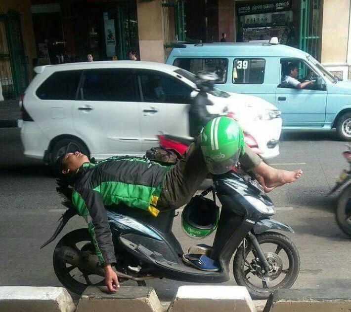Pengemudi ojek online tidur di atas motor