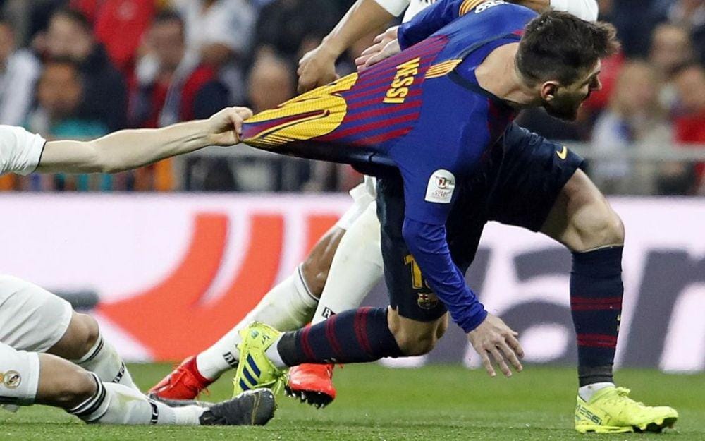 Luka Modric menarik jersey Lionel Messi di El Clasico tahun lalu. Twitter/@FCBarcelona