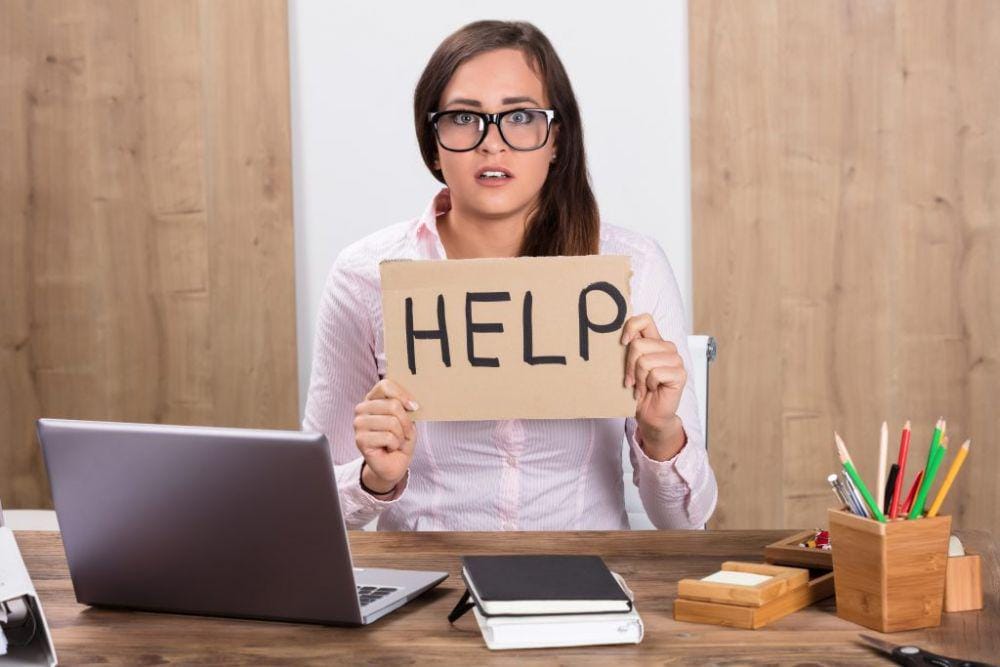 Businesswoman Holding Help Sign At Workplace