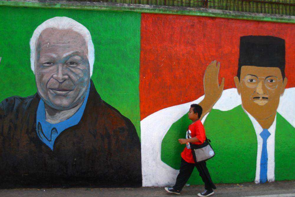 Seorang pelajar melintas di depan mural mantan Presiden RI Soeharto dan BJ Habibie (ANTARA FOTO/Ari Bowo Sucipto)