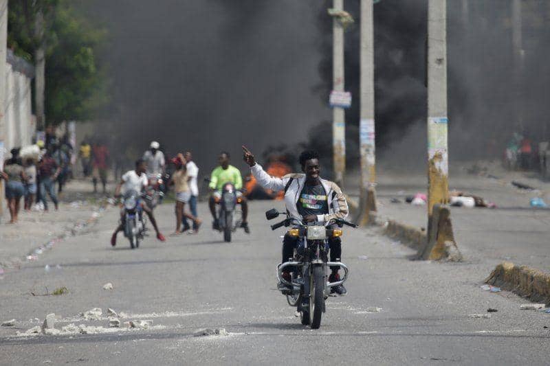 Seorang pria mengangkat tangan saat mengendarai sepeda motor setelah melewati barikade terbakar, sementara orang-orang melakukan aksi protes atas langkanya bahan bakar, di jalanan Port-au-Prince, Haiti, pada 2 September 2019. ANTARA FOTO/REUTERS/Andres Martinez Casares