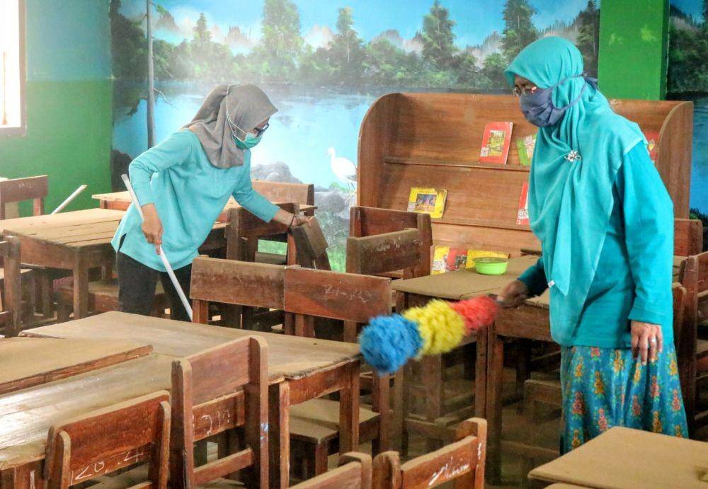 Beberapa guru tampak membersihkan debu di ruang kelas sebuah sekolah di Kota Batu. IDN Times/ Alfi Ramadana