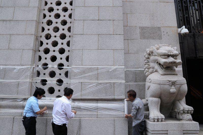Pekerja membungkus gedung Bank Sentral Tiongkok dengan plastik untuk melindungi dari aksi vandalisme, di Hong Kong, pada 30 September 2019. ANTARA FOTO/REUTERS/Susana Vera