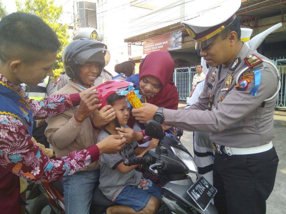 Kasatlantas Polres Madiun AKP Jimmy Heriyanto Manurung membagikan helm kepada anak-anak yang dibonceng sepeda motor dalam Operasi Zebra 2019 di jalur Madiun - Nganjuk, Rabu (30/10). IDN Times/Nofika Dian Nugroho