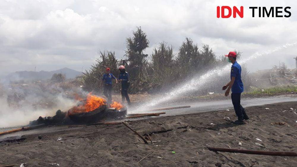 Petugas padamkan api dari ban yang dubakar petambak. IDN Times/Daruwaskita