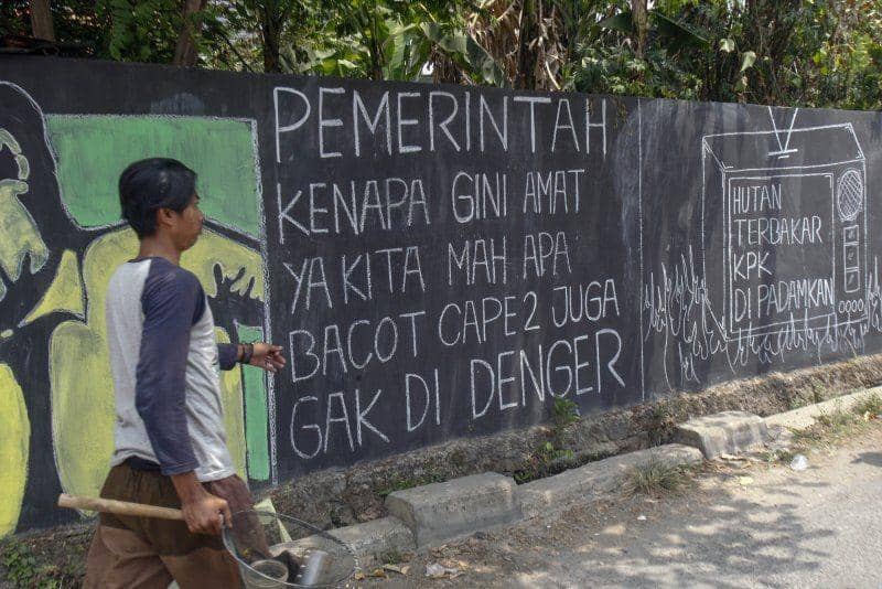 Warga melintas di samping mural bertema kritik sosial di Jalan Cikaret, Cibinong, Bogor, Jawa Barat, pada 3 Oktober 2019. ANTARA FOTO/Yulius Satria Wijaya