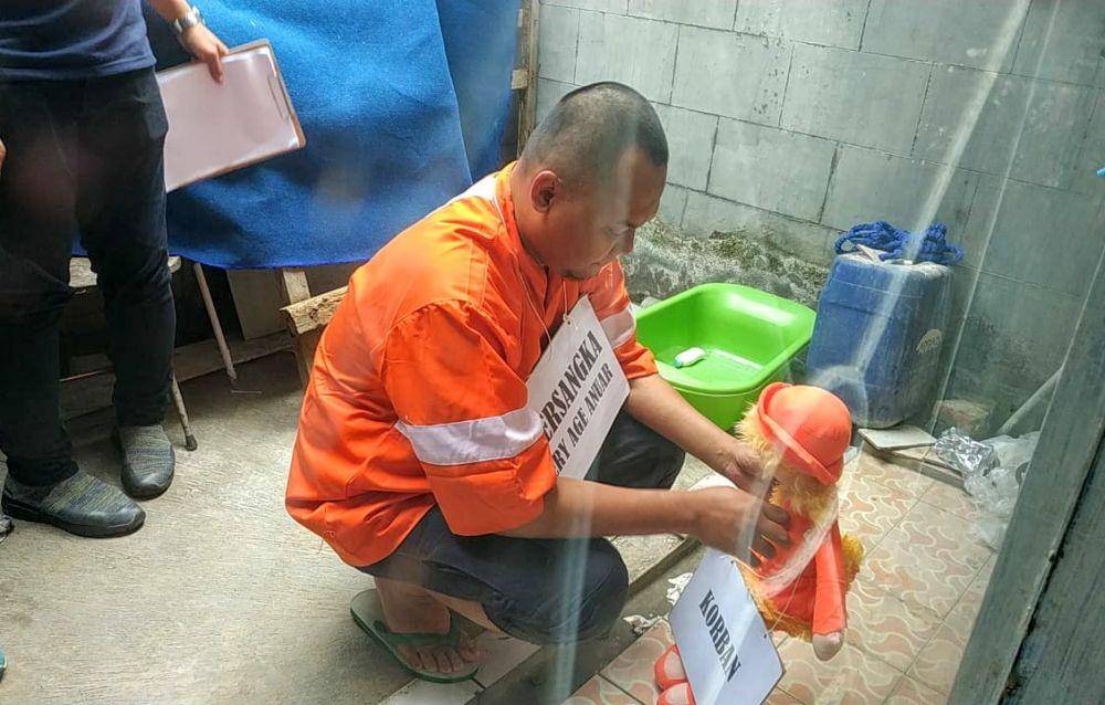 Tersangka EA saat melakukan peragaan tindakan aniaya kepada putri tirinya, Kamis (7/11/2019). IDN Times/ Alfi Ramadana