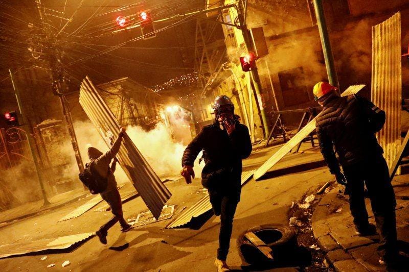 Demonstran menggunakan masker gas dan membawa barikade berlari saat terjadi bentrokan antara penentang Presiden Bolivia Evo Morales dengan pendukung pemerintah, di La Paz, Bolivia, pada 7 November 2019.  ANTARA FOTO/REUTERS/Kai Pfaffenbach