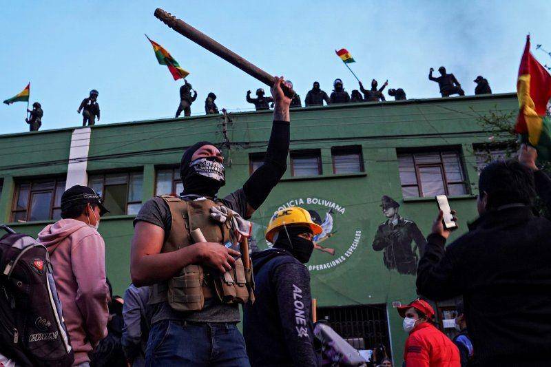 Lawan dari mantan Presiden Bolivia Evo Morales mengangkat kayu saat polisi berdiri di atap kantor pusat mereka, di Cochabamba, Bolivia, pada 8 November 2019. ANTARA FOTO/REUTERS/Danilo Balderrama