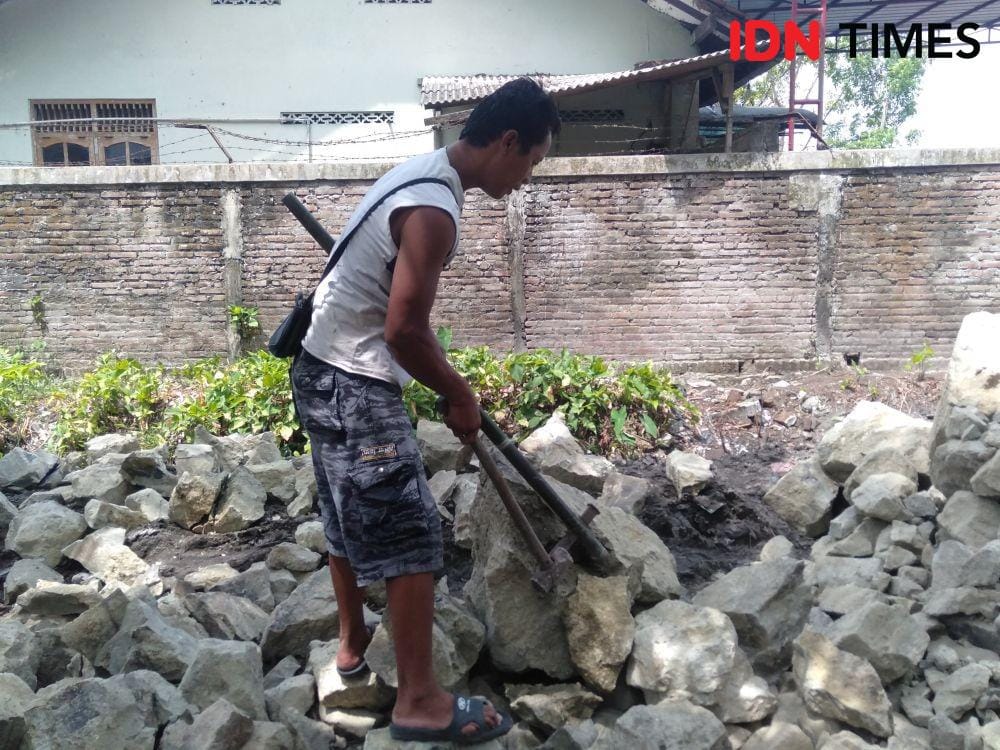 Ilustrasi pekerja sedang memecah batu untuk pembangunan talut. IDN Times/Daruwaskita