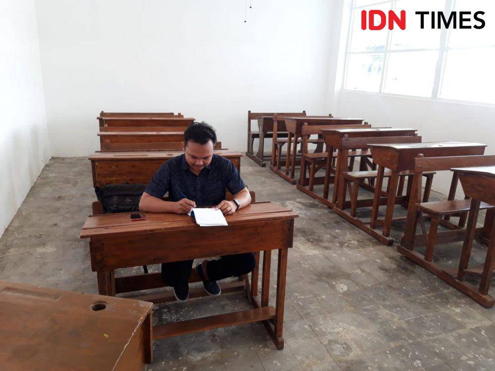Seorang pengunjung Museum Pendidikan tampak menghayati, seolah-olah bersekolah pada era kolonial. IDN Times/Fitria Madia