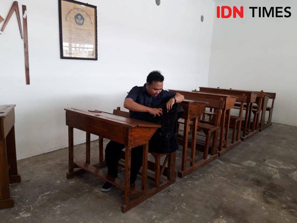 Seorang pengunjung Museum Pendidikan tampak menghayati, seolah-olah bersekolah pada era kolonial. IDN Times/Fitria Madia