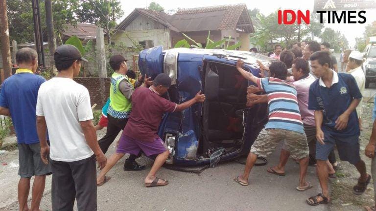 Anggota Polsek Bobotsari gotong royong bersama warga membalik mobil yang terguling setelah menabrak pengendara sepeda motor di Jalan Raya Dusun Karangsari, Bobotsari. (Istimewa)