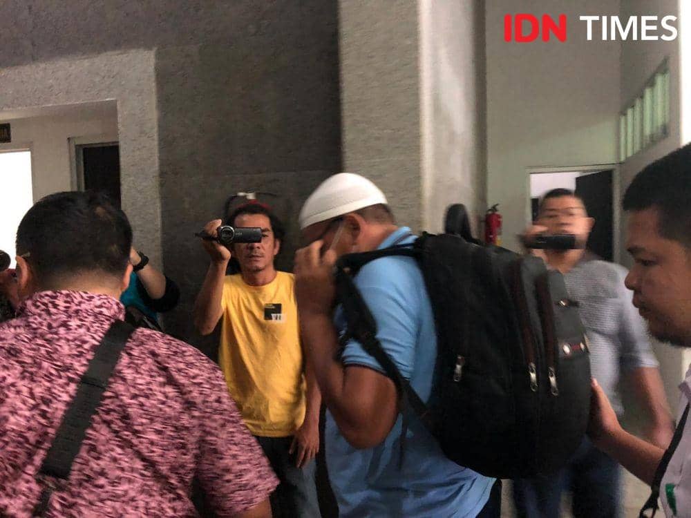 Terdakwa menutup muka dengan masker dan kacamata (IDN Times/Rangga Erfizal)