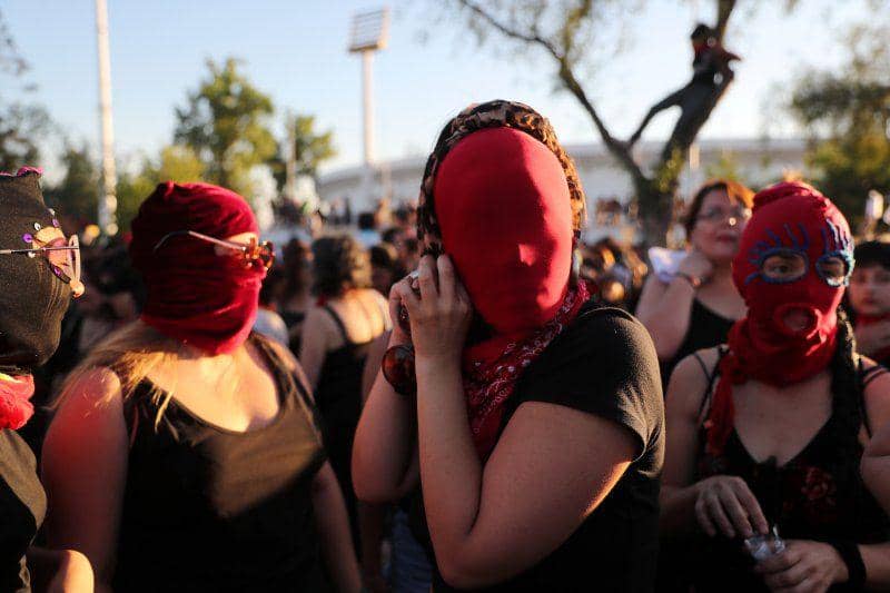 Aktivis hak asasi perempuan dan warga memakai masker saat aksi protes menentang kekerasan terhadap wanita dan pemerintah di Santiago, Chile, pada 4 Desember 2019. ANTARA FOTO/REUTERS/Ivan Alvarado