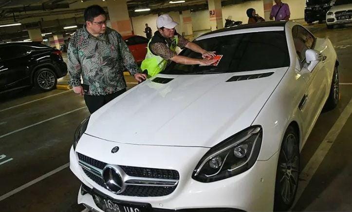 (Fungsional pada Koordinasi Supervisi dan Pencegahan Korwil 3 Komisi Pemberantasan Korupsi (KPK) Friesmount Wongso (kiri) mengamati Petugas Samsat Jakarta Utara Kukun Kurnadi (kanan) menempelkan stiker 'Objek Pajak' pada mobil mewah saat razia supervisi pencegahan pajak mobil mewah di Apartemen Regatta, Jakarta Utara, Kamis (5/12/2019). ANTARA FOTO/M Risyal Hidayat