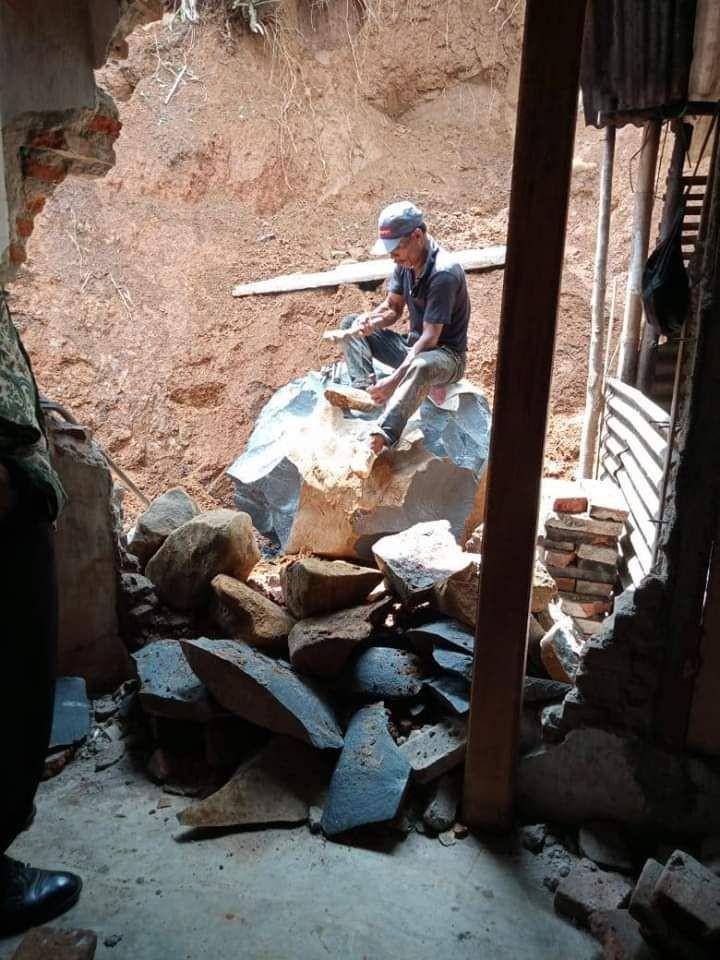 Seorang pekerja memecah batu yang terbawa longsor di di Dusun Sawangan Rt 01/Rw 06 Desa Bantarpanjang, Kecamatan Cimanggu, Kabupaten Cilacap, Selasa (17/12). Dok BPBD Cilacap