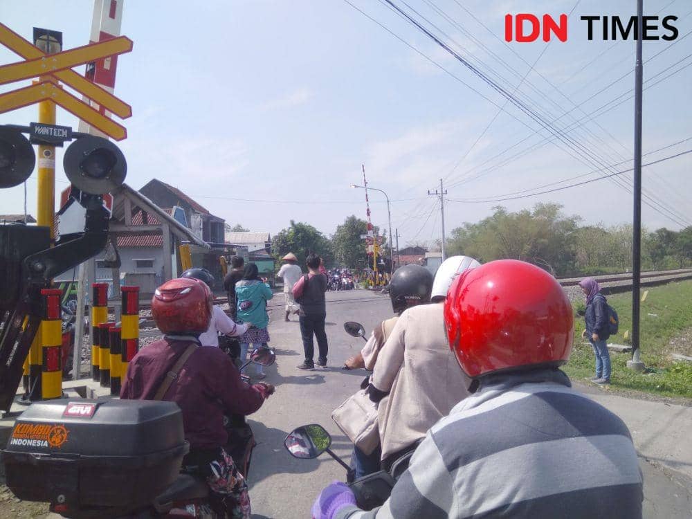 Sejumlah pengguna jalan berhenti saat kereta api melintas di perlintasan sebidang yang palang pintu ya belum dioperasionalkan. IDN Times/Nofika Dian Nugroho