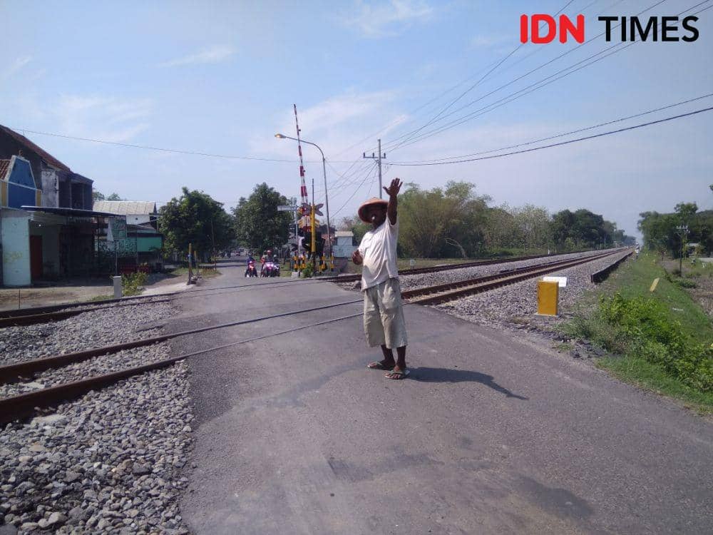 Seorang relawan sedang mengatur lalu lintas saat kereta api melintas di perlintasan sebidang yang masuk wilayah Desa/Kecamatan Wonoasri, Kabupaten Madiun. IDN Times/Nofika Dian Nugroho