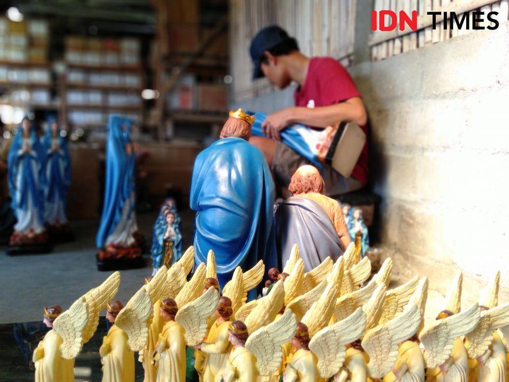 Seorang pekerja sedang menyelesaikan pengecatan patung raja-raja. IDN Times/Daruwaskita