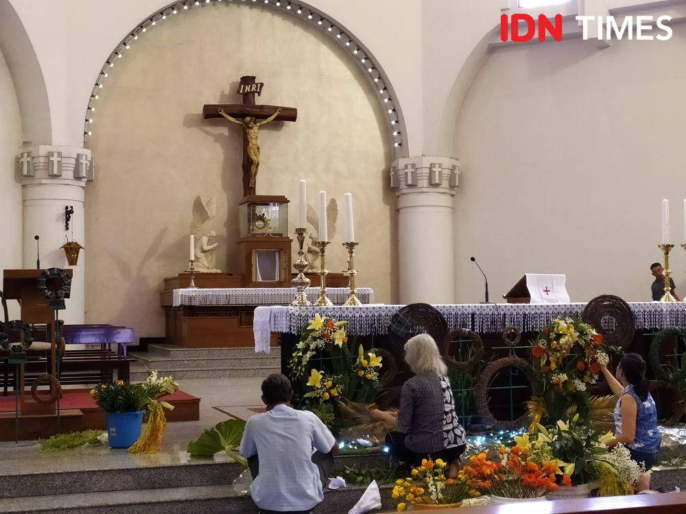 Dua wanita saat memasang hiasan bunga dibawah patung Yesus Kristus di Katedral Semarang. IDN Times/Fariz Fardianto
