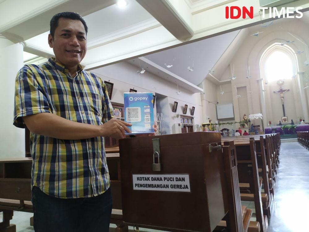 Romo Tanto, pastor Gereja Paroki Kebondalem saat memasang barcode GoPay di kotak amal gerejanya. IDN Times/Fariz Fardianto