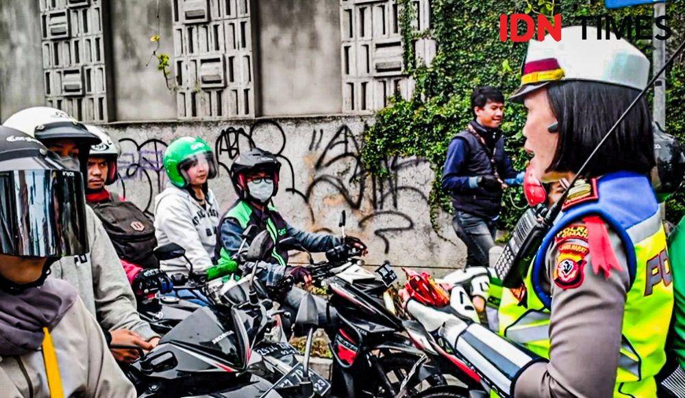 Petugas polisi bagi-bagi jajanan gratis saat atur macet di jalur wisata Lembang. (IDN Times/Bagus F)
