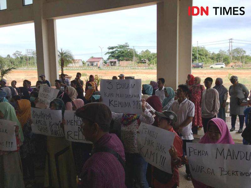 Warga terdari ibu - ibu  Gang Buaya dari tiga RT menunjukan poster dari kartu ketika demo di depan kantor DPRD PPU (IDN Times/ Ervan Masbanjar)