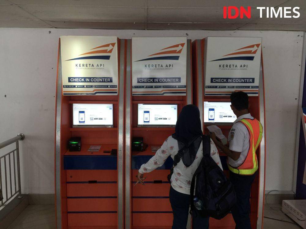 Seorang petugas kereta api membantu penumpang melakukan check in tiket (IDN Times/Prayugo Utomo)