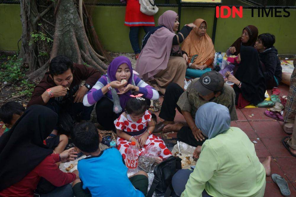 Salah satu keluarga tampak menikmati bekal makan siang yang dibawa saat mengunjungi Kebun Binatang Surabaya, Rabu (1/1). IDN Times/Fitria Madia