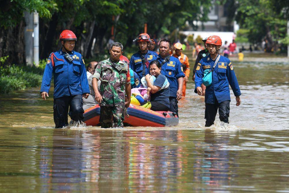 Anggota TNI dan Dinas Pemadam Kebakaran dan Penanggulangan Bencana (Damkar dan PB) DKI Jakarta menarik perahu karet yang dinaiki warga saat melintasi genangan banjir di kawasan Bungur Besar Raya, Jakarta. ANTARA FOTO/M Risyal Hidayat