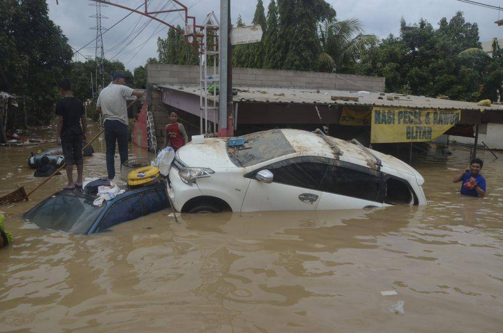 Sejumlah warga menaiki mobil yang terdampak banjir di Perumahan Pondok Gede Permai Bekasi, Jawa Barat. (ANTARA FOTO/Fakhri Hermansyah)