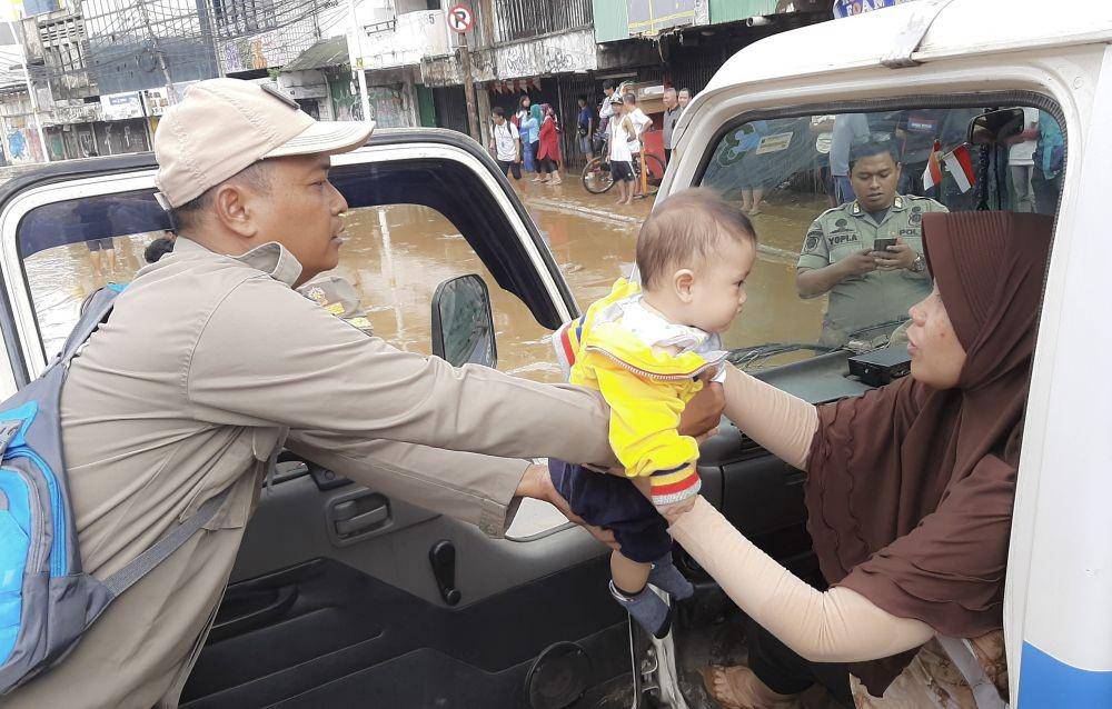Anggota Satpol PP DKI Jakarta menggendong bayi saat mengevakuasi korban banjir di Jalan Jatinegara Barat, Kampung Pulo, Jakarta. ANTARA FOTO/Nova Wahyudi