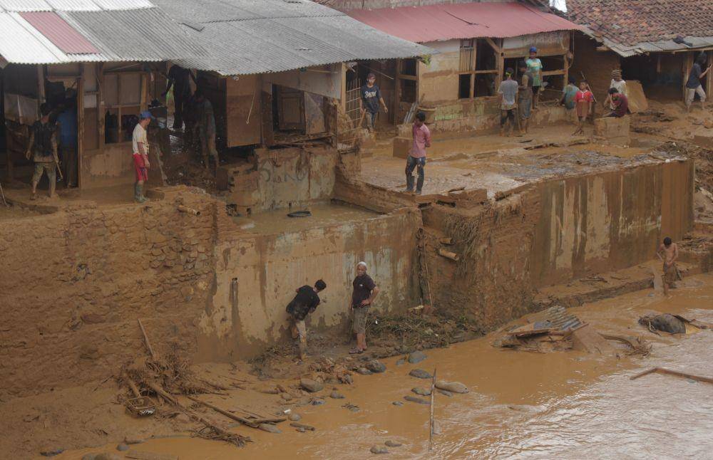 Sejumlah warga bergotong-royong membersihkan lumpur dampak serangan banjir bandang di Kampung Lebak Gedong, Cipanas, Lebak, Banten, Rabu (1/1). (ANTARA FOTO/Weli Ayu Rejeki)