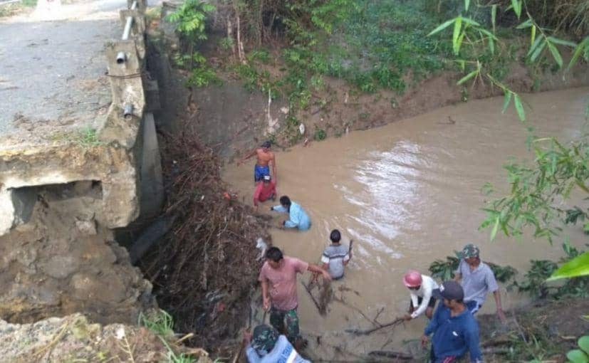 Warga membersihkan tumpukan sampah kayu yang menutupi aliran sungai. IDN Times/istimewa