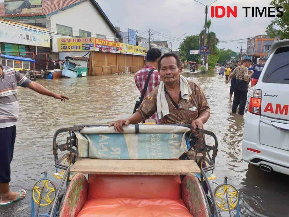 Adang, tukang becak yang mengantarkan warga melewati banjir di Jalan Nangka Raya, Kota Bekasi (IDN Times/Vanny El Rahman)