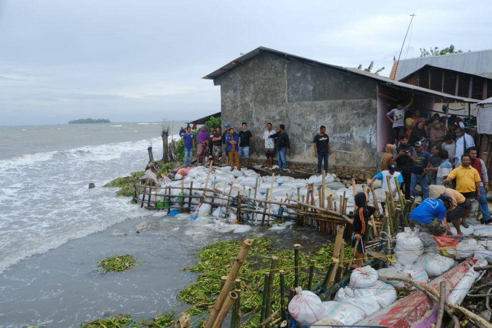 Warga memanfaatkan karung pasir untuk menahan air laut di Pantai Galesong Takalar, Selasa (7/1). Humas Pemprov Sulsel