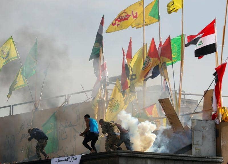 Pengunjuk rasa dan pejuang milisi menyelamatkan diri dari gas airmata dilemparkan anggota keamanan kedutaan Amerika Serikat, saat memprotes serangan udara di pangkalan milik Hashd al-Shaabi (pasukan paramiliter), di depan kedutaan di Baghdad, Irak, pada 1 Januari 2020. ANTARA FOTO/REUTERS/Thaier al-Sudani