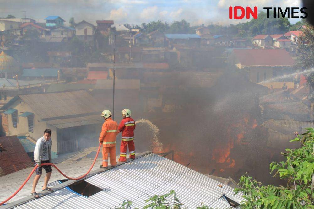 Petugas dan warga naik atap rumah untuk memadamkan kebakran. (IDN Times/Surya Aditya)