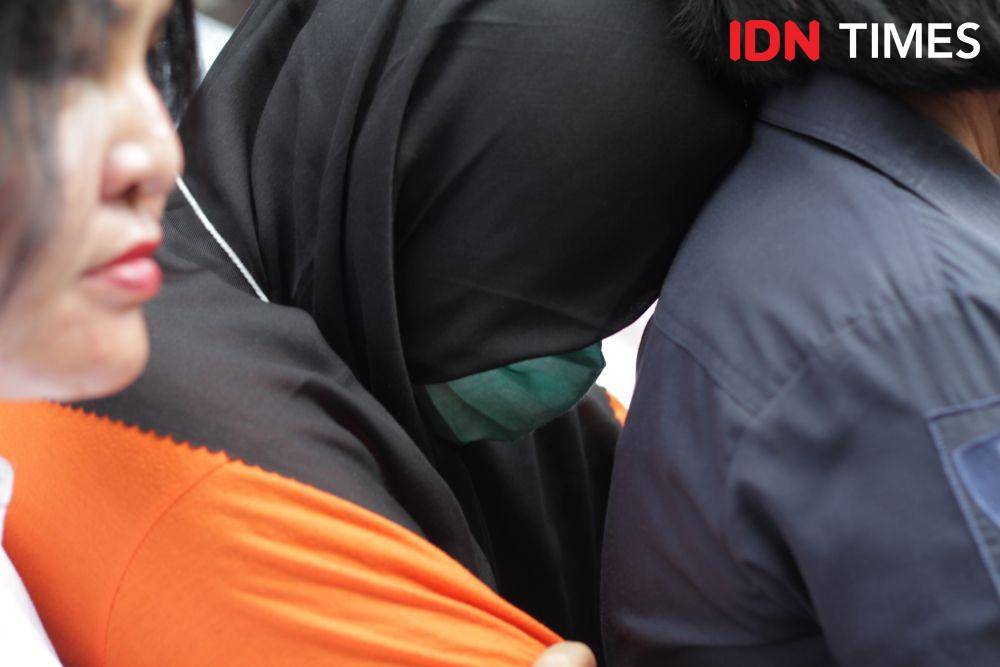 ZH (pakai masker) terus tertunduk selama rekonstruksi pembunuhan suaminya, Jamaluddin (IDN Times/Prayugo Utomo)