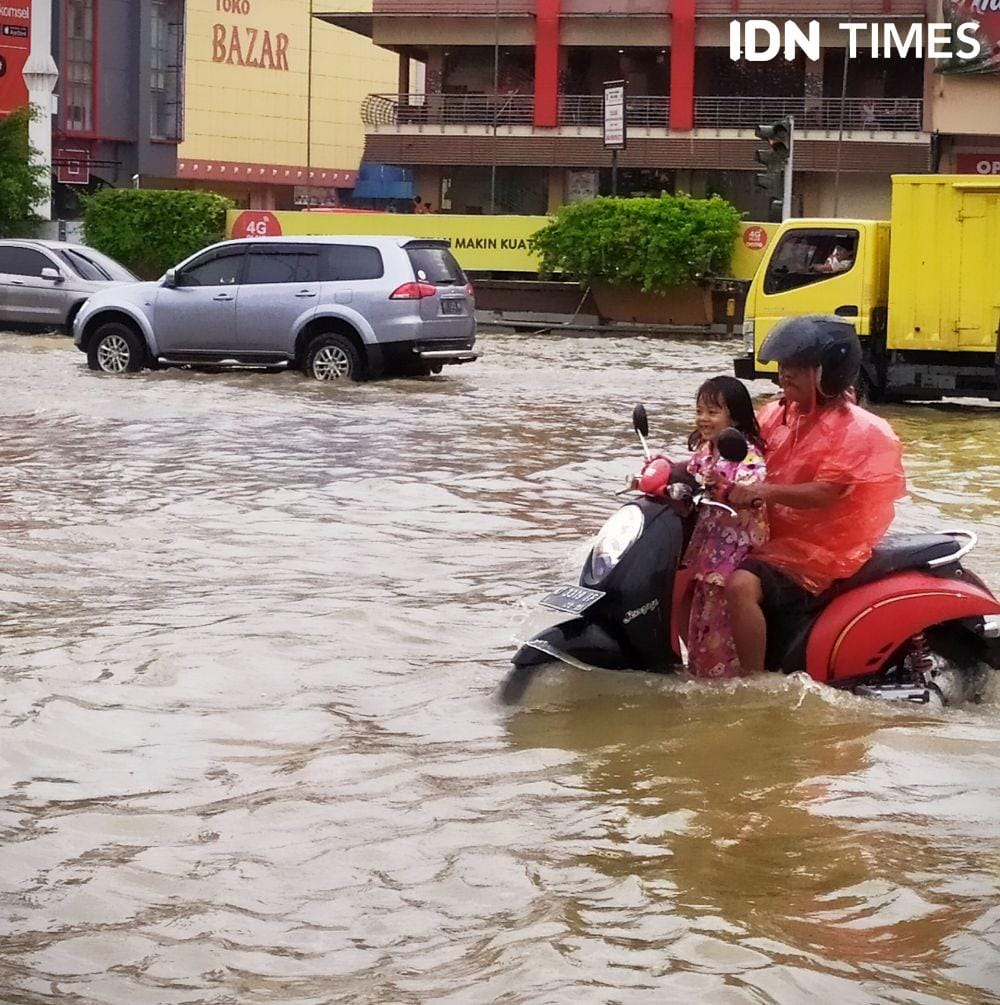 Bocah ini tampak riang saat melewati banjir di Simpang Empat Mal Lembuswana Samarinda bersama sang ayah (IDN Times/Yuda Almerio)