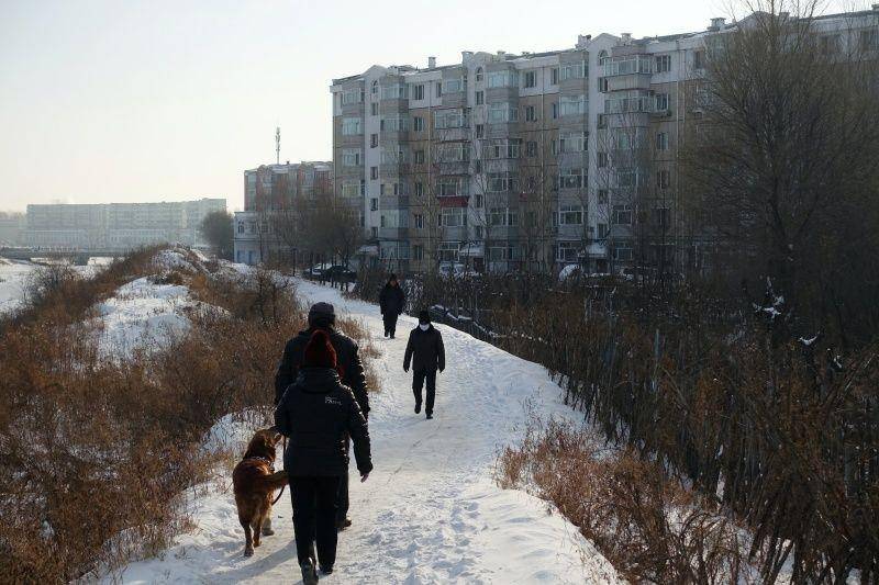 Warga berjalan di sebelah gedung tempat tinggal di kota penghasil batubara Hegang, provinsi Heilongjiang, timur laut Tiongkok, pada 2 Januari 2020. Gambar diambil 2 Januari 2020. ANTARA FOTO/REUTERS/Ryan Woo