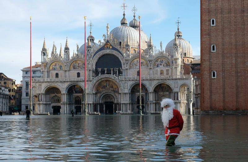 Warga berjalan di St. Mark's Square yang tergenang banjir saat gelombang pasang di Venesia, Italia, pada 23 Desember 2019. ANTARA FOTO/REUTERS/Manuel Silvestri